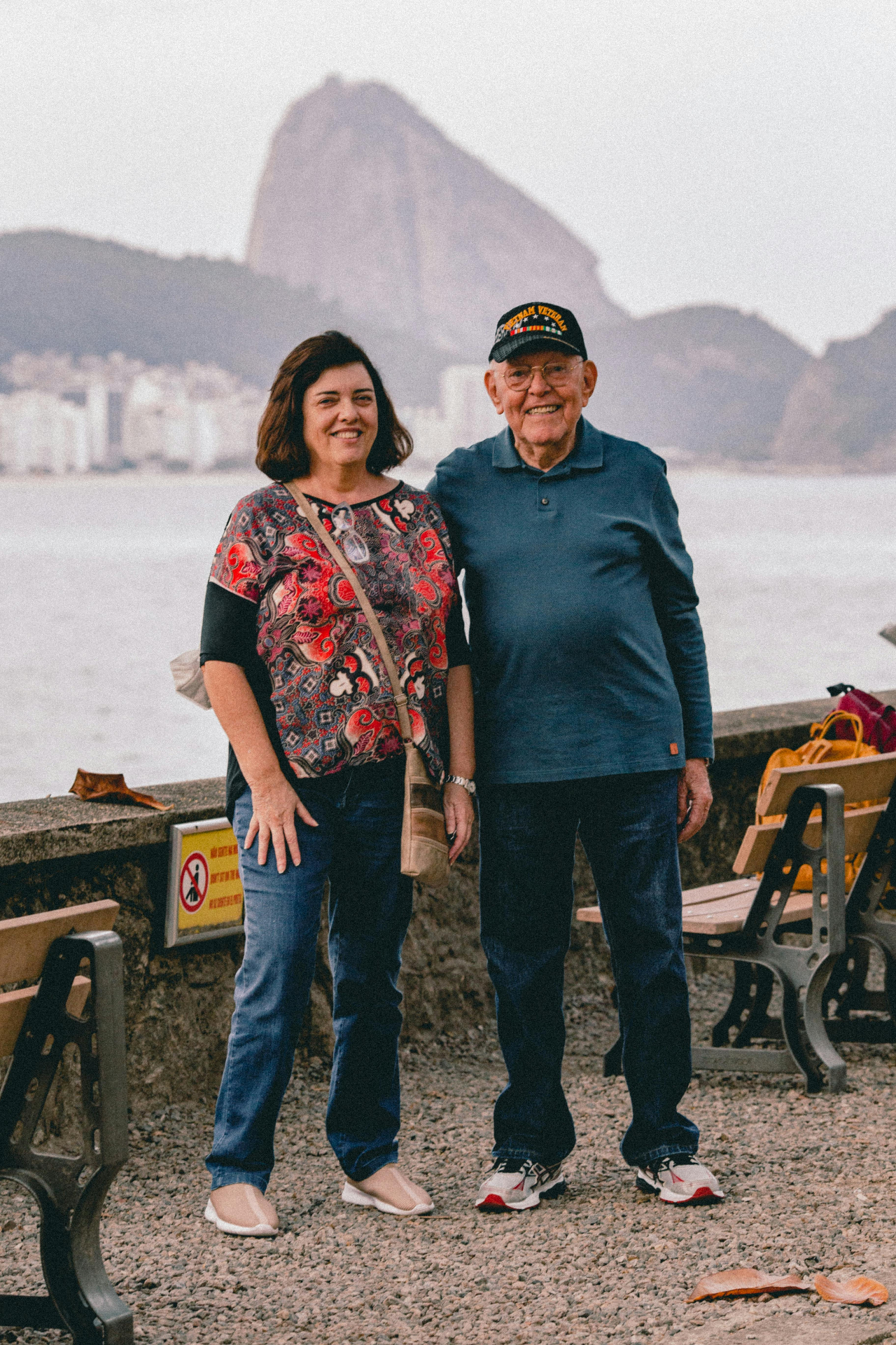 Casal próximo ao mar com Pão de Açúcar ao fundo